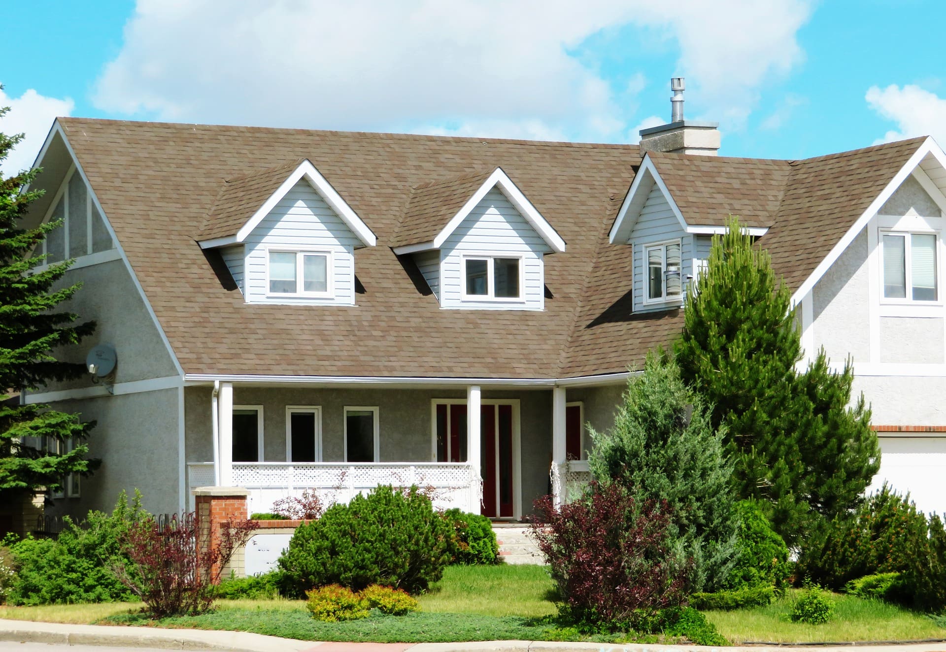 A large white house with brown roof and green lawn.