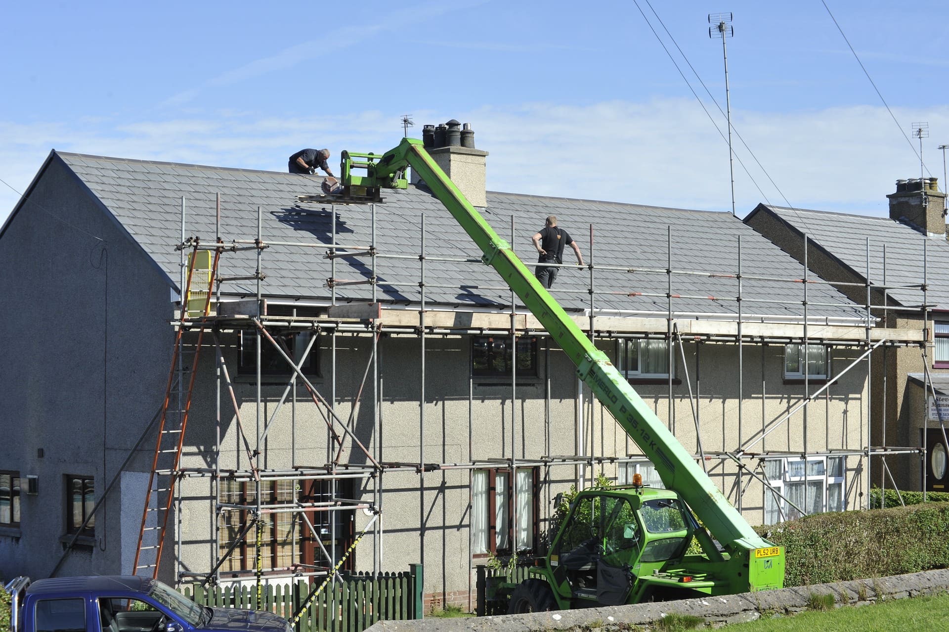 A green crane is on top of a building