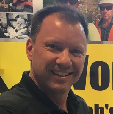 A man standing in front of a yellow sign.