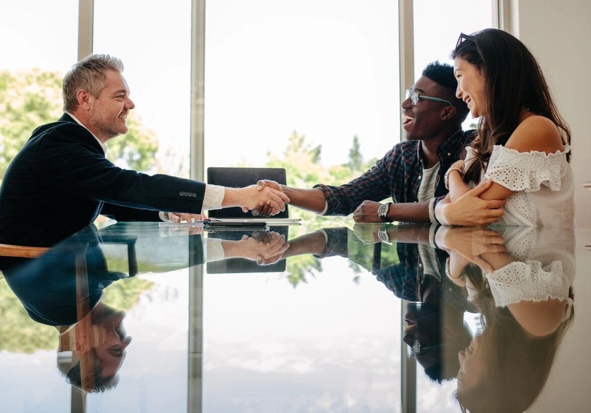 A group of people sitting around a table shaking hands.